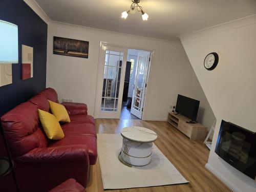 a living room with a red couch and a tv at Duxford Haven in Duxford