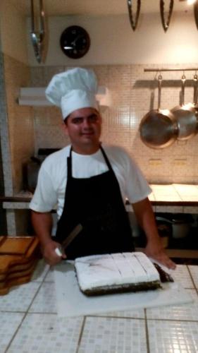 a chef standing in a kitchen cutting a cake at Celeste Mountain Lodge in Bijagua