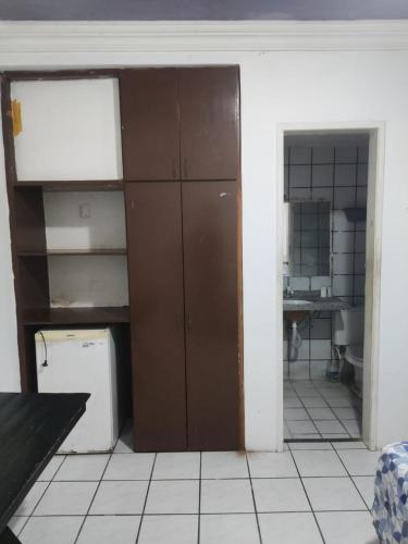 a room with a kitchen with a refrigerator and a shelf at Hotel Panorama do Mar - Praia do Futuro in Fortaleza