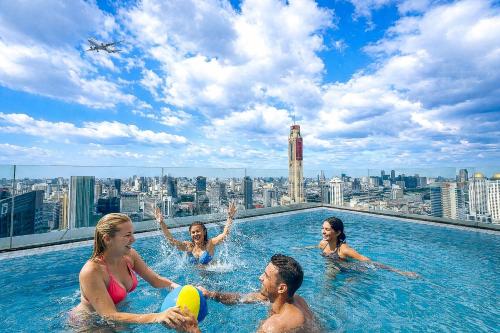a group of people in a pool on the roof of a building at Luxury Downtown Bangkok 2BR 2BA Sky Pool Gym 5MIN Walk to Siam Paragon in Bangkok