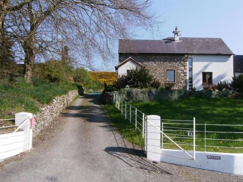 a house with a white fence next to a road at The Village Studio Apartments in Moate