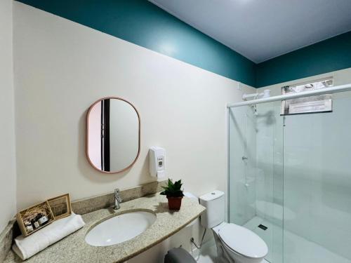 een badkamer met een wastafel, een toilet en een spiegel bij Muira Stay Belém Hostel in Belém