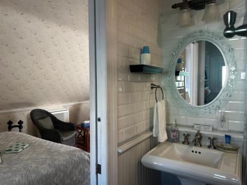 a bathroom with a sink and a mirror and a bed at Beauclaires Bed & Breakfast in Cape May
