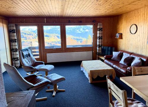 a living room with a couch and chairs and a window at Chalet Heide Beatenberg in Beatenberg