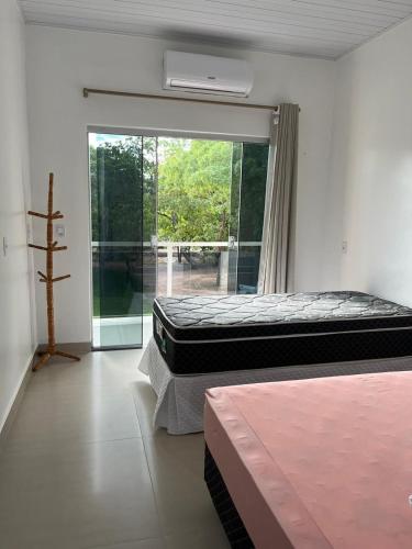 two beds in a room with a sliding glass door at Chácara Fim de Tarde in Barra do Garças