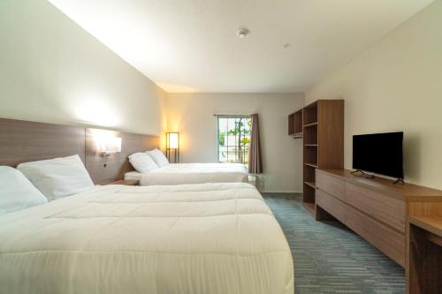 a hotel room with two beds and a flat screen tv at Efficiency De Luxe Sulphur Near Lake Charles I 10 in Sulphur