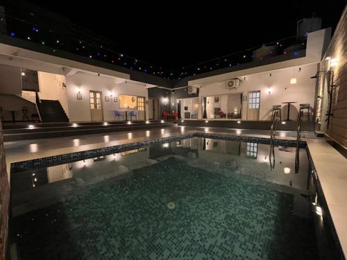 a swimming pool at night with lights in it at Casa Oceanus - Sea Facing Forest View Room - Ganpatipule in Nevra