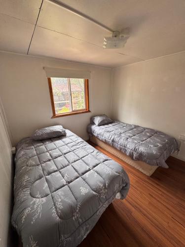 two beds in a small bedroom with a window at Casa Maya Modern central and pet friendly in Futaleufú