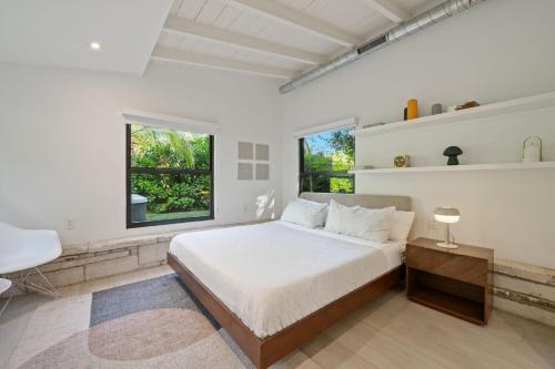 a white bedroom with a large bed and two windows at Coconut Grove Mid-Century Jungle Oasis in Miami