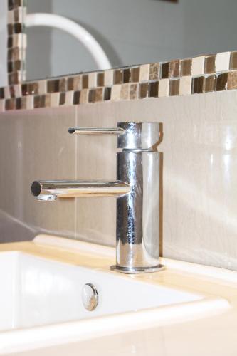 a bathroom sink with a chrome water faucet at Residencial Victoria Said in Linares