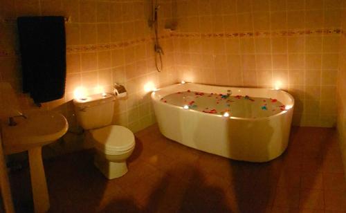 a bathroom with a tub and a toilet and lights at Jasmine's Bungalow in Ban Saiyuan (1)