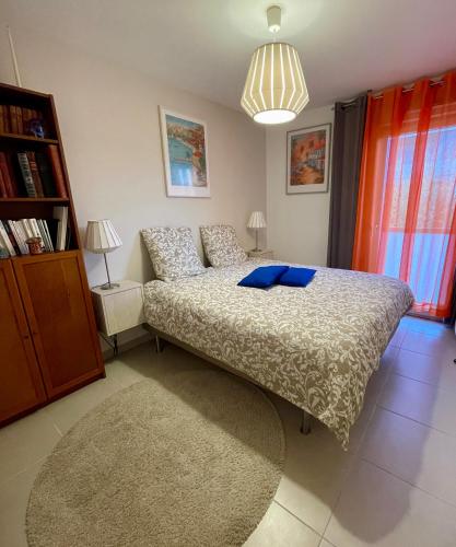 a bedroom with a bed with blue pillows on it at Flo location Fréjus in Fréjus