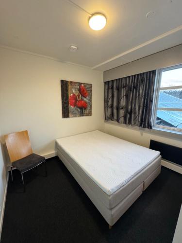 a bedroom with a bed and a chair and a window at Siggjo Guesthouse Bømlo and Stord in Mosterhamn
