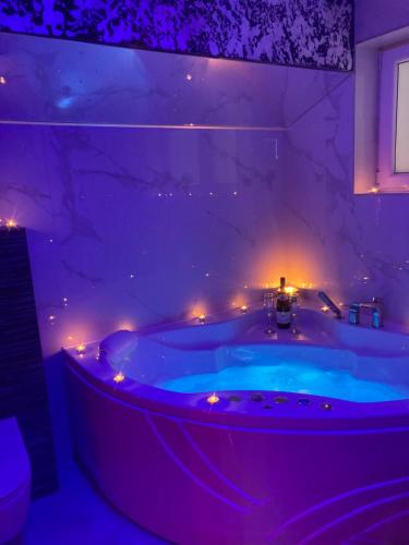 a purple bathroom with a tub with lights in it at Star&spa in Niš