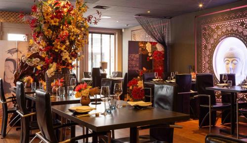 a dining room with tables and chairs and flowers at Hampshire Hotel Petit Nord in Hoorn