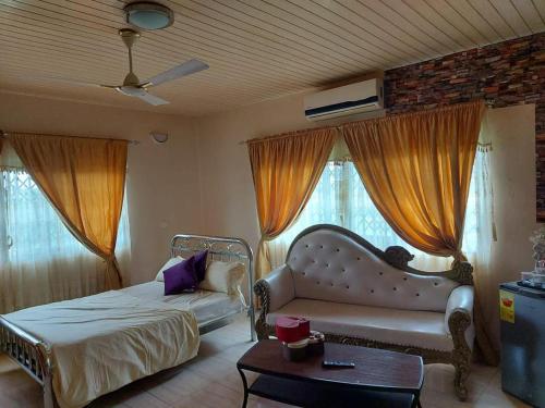 a bedroom with a bed and a couch and windows at Osprise Residencies in Tema