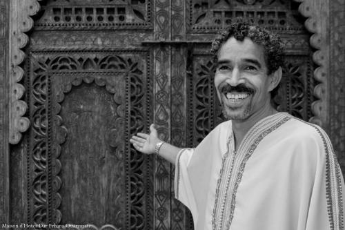 a man standing in front of a wooden door at Maison d'hôtes Dar Farhana in Ouarzazate