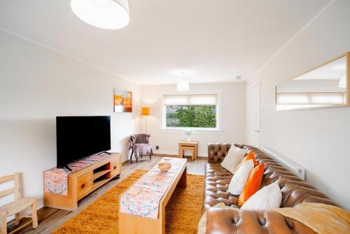 a living room with a couch and a tv at Stylish Stirling home with stunning views in Stirling