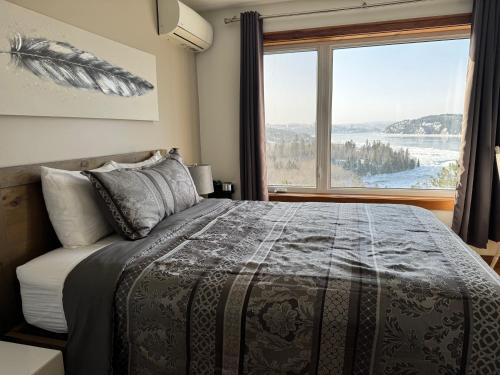una camera da letto con un letto e una grande finestra di Gîte du Haut des Arbres a Saguenay