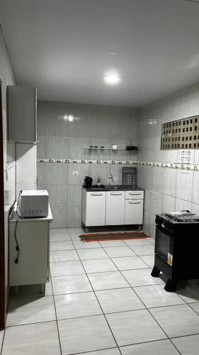 a large kitchen with white tiled floors and appliances at Casa Japaratinga in Japaratinga