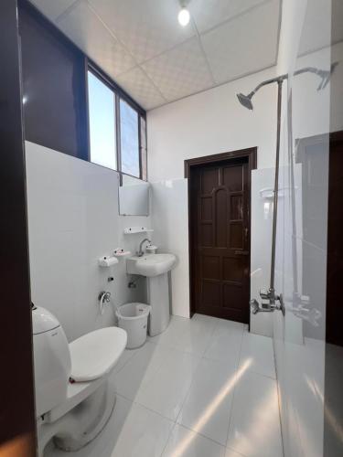 a bathroom with a toilet and a sink and a shower at Elysium Inn in Abbottabad