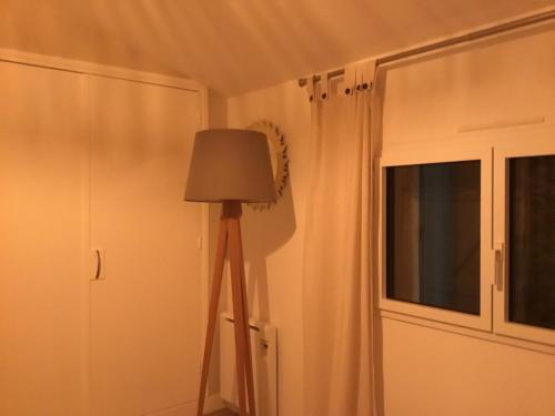 a lamp in a corner of a room with a window at Chez David Tony in La Celle-sous-Gouzon