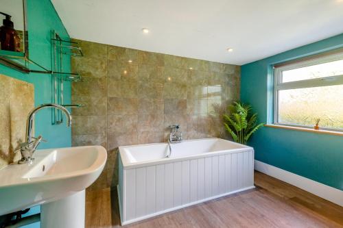 a bathroom with a tub and a sink and a window at 3 Bed in Morfa Nefyn oc-wag720 in Morfa Nefyn