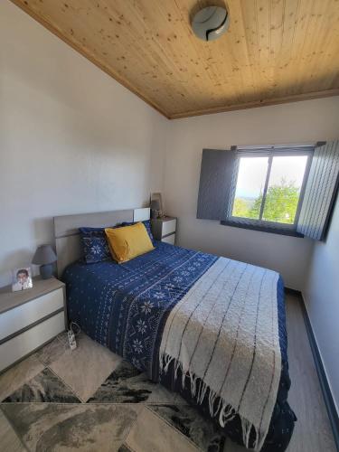a bedroom with a bed with a blue comforter and a window at Portela ALR in Portela da Memória