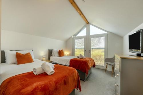 a bedroom with two beds and a tv and a window at 4 Bed in Aberarth oc-g30835 in Aberaeron