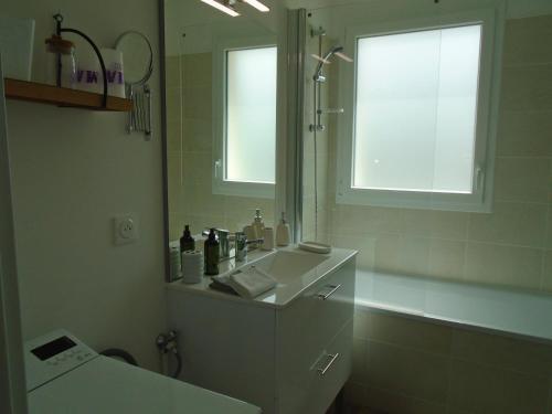 une salle de bains avec un lavabo et un miroir dans l'établissement Bagatelle, à Courseulles-sur-Mer