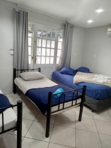 a bedroom with two beds and a window at Pousada Central Quarto 1 in Joinville