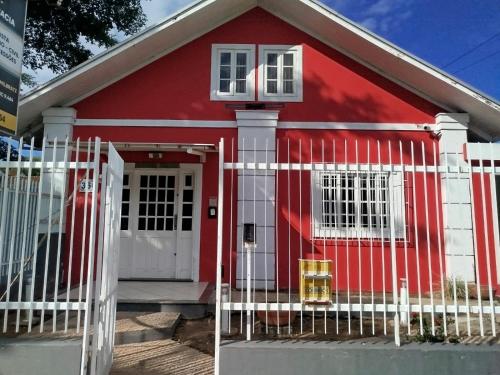 a red house with a white fence in front of it at Pousada Central Quarto 1 in Joinville