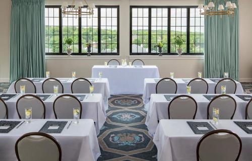 a room with white tables and chairs and windows at Graduate by Hilton Charlottesville in Charlottesville