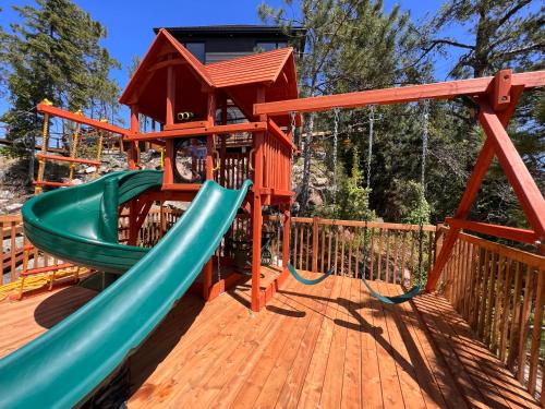 a playground with a slide on a wooden deck at Gîte du Haut des Arbres in Saguenay