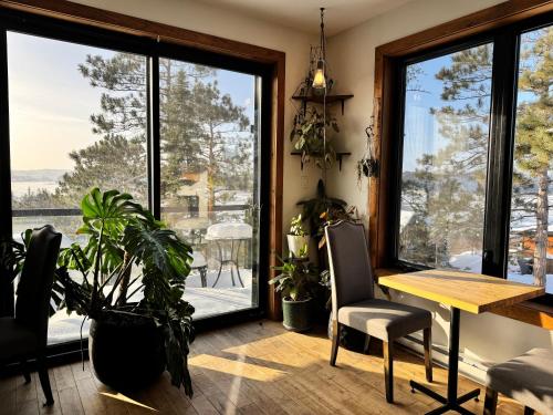 una sala da pranzo con tavolo, sedie e finestre di Gîte du Haut des Arbres a Saguenay