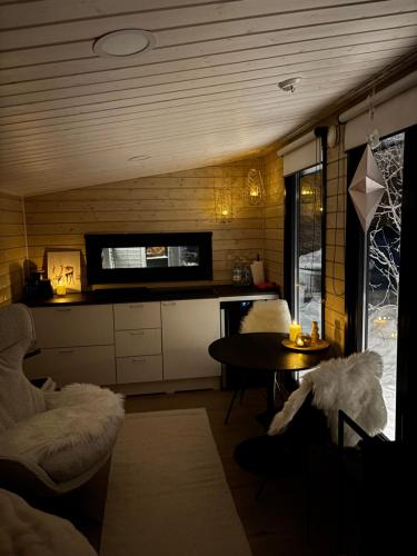 a living room with a table and a kitchen at Palas Experience Olkkajärvi Resort in Rovaniemi