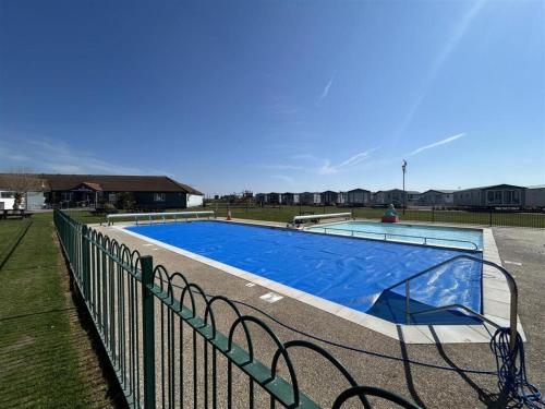a large blue swimming pool next to a fence at Seaview Holiday Park - 2 bedroom sleeps 6 Family & Pet friendly in Chestfield