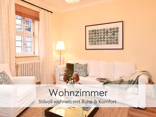 a living room with a white couch and a table at Amalias Altstadtquartier - Apartment mit Aufzug & Garten in der Hinterburg Schlitz - 2 Schlafzimmer, Parkplatz, Altstadtflair für Paare & Ruhesuchende in Schlitz