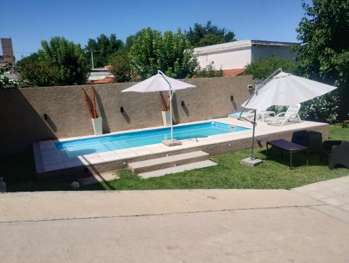 a swimming pool with two umbrellas and two chairs at Departamentos Mama carmen in Mina Clavero