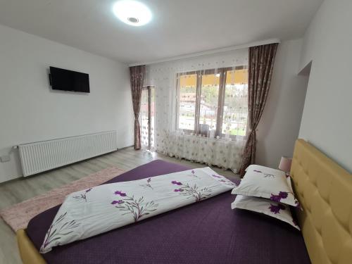a bedroom with a large bed and a window at Agropensiunea Maya-Andrei in Novaci-Străini