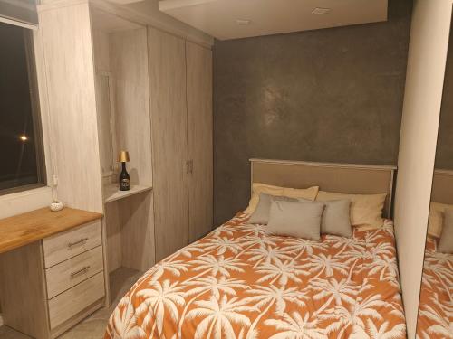 a bedroom with a bed with an orange and white blanket at Coastal Calm The Cove 2 in Flic-en-Flac