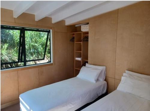 two beds in a small room with a window at Ponga House - Kaitoke Waters in Okupu
