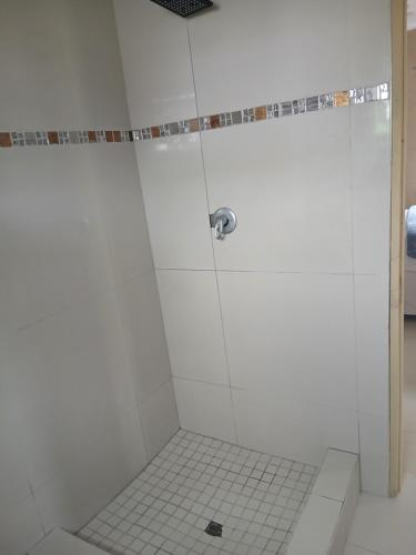 a bathroom with a shower with white tile at Cozy Road Lodge in Sihangwane