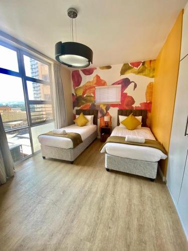 a bedroom with two beds and a painting on the wall at Oceanic 2 Bedroom Apartment - Ocean and Park View - Self-Catering in Durban