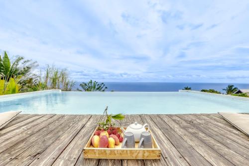 a tray of fruit on a table next to a swimming pool at Comme un bateau sur l'océan in Saint-Leu