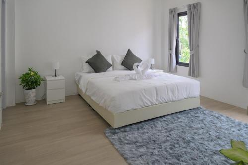 a white bedroom with a white bed with a blue rug at Zen Beach Lake Villa 3 - orchid villa in Haad Chao Phao