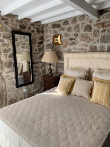 a bedroom with a white bed with a stone wall at 3 Marias da Fonte in Lousa