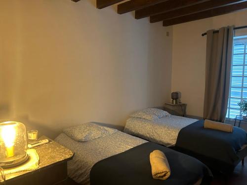 une chambre avec deux lits et une lampe et une fenêtre dans l'établissement Gîte la plotuère, à Gy-en-Sologne