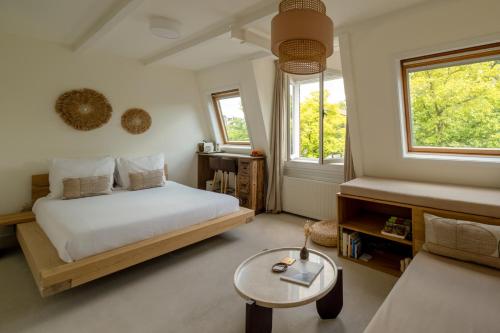 a bedroom with a bed and a table and two windows at Canal View Stay Amsterdam in Amsterdam