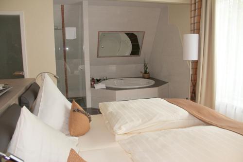 Schlafzimmer mit einem Bett, einem Waschbecken und einer Badewanne in der Unterkunft Am Schlosspark in Worms